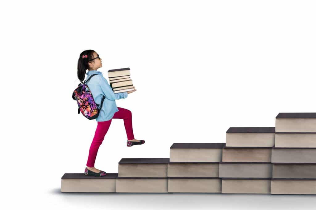Little student holding pile of books in studio